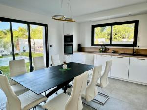a kitchen with a black table and white chairs at Villa Vanille Cap d Agde Luxe piscine chauffée 5 étoiles in Le Grau-dʼAgde