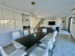 a dining room with a black table and white chairs at Villa Vanille Cap d Agde Luxe piscine chauffée 5 étoiles in Le Grau-dʼAgde