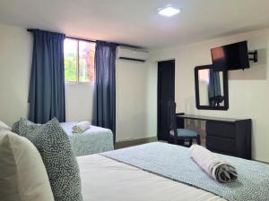 een slaapkamer met twee bedden, een bureau en een spiegel bij Hotel Olimpo in La Romana