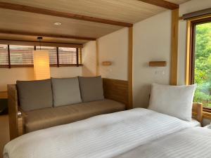 a bedroom with a bed and a couch and a window at MY LODGE Naoshima in Naoshima