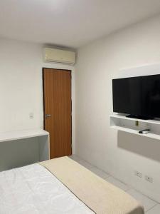 a white room with a bed and a flat screen tv at Flat Fazenda Monte Castelo in Bezerros