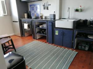 a kitchen with blue cabinets and a sink and a rug at Casa Monte Queimado in Horta