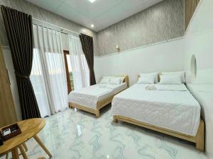 a bedroom with two beds and a table and a window at Khách sạn Đức Lộc Phát in Kiến Ðức +30 photos