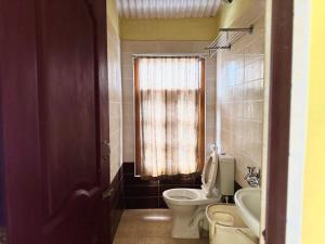 a bathroom with a toilet and a sink and a window at Satya Anand Pure Veg and Non Alcoholic Cottage in Coonoor +245 photos