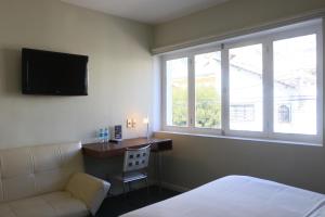 a bedroom with a bed and a desk and a television at Casa Fusion Hotel Boutique in La Paz