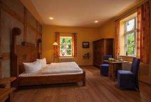 Schlafzimmer mit einem Bett, einem Schreibtisch und Fenstern in der Unterkunft Burghotel Stargard in Burg Stargard