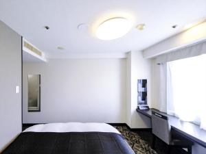 a hotel room with a bed and a window at APA Hotel Tottori Ekimae Minami in Tottori