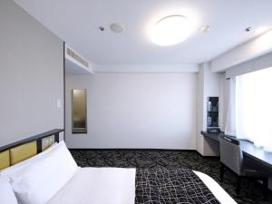 a hotel room with a bed and a window at APA Hotel Tottori Ekimae Minami in Tottori