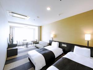 a hotel room with two beds and a couch at APA Hotel Tottori Ekimae Minami in Tottori