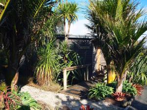 un giardino con palme e una casa con cancello di Tutiri in Oneroa - Stay Waiheke a Oneroa