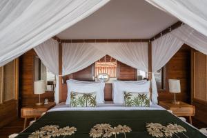 - une chambre avec un lit vert et des oreillers blancs dans l'établissement Anna Villas by Sumba-Beach, à Memboro