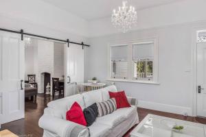 ein weißes Wohnzimmer mit einem weißen Sofa und roten Kissen in der Unterkunft Warm Inviting, and Luxurious The Manor in Sandy Bay