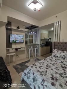 a bedroom with a bed and a tv and a kitchen at Inspiria Condo Davao - Olivia's Haven in Davao City