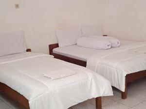 two twin beds with white sheets in a room at Hotel Wisata in Labuan Bajo