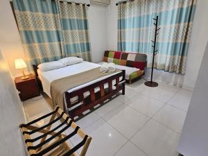 a bedroom with a bed and a chair in it at FIJI HOME Apartment Hotel in Suva