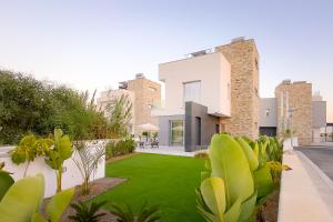 a house with a yard with green grass at City Napa Seaview Villas in Ayia Napa