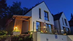 a large white house with lights on it at night at Wonder Home - Domki górskie wolnostojące z prywatnymi tarasami - zielona okolica in Karpacz
