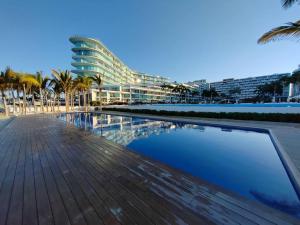 a swimming pool in front of a building with palm trees at Beachfront Bliss at Aria Ocean Flamingos in Nuevo Vallarta