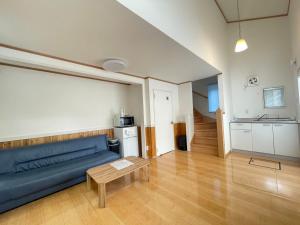 a living room with a blue couch and a table at キズキノホテル in Morioka