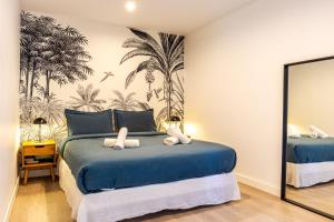 a bedroom with a bed with blue sheets and palm trees on the wall at Olympe-Free carpark, 7 min from Old town, Spacious & Calm in Annecy