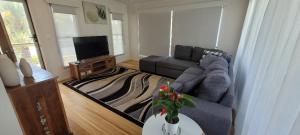 a living room with a couch and a tv at Recovery On Discovery Holiday House in Agnes Water