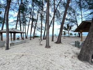 a beach with trees and a bench on the sand at Barokah Resort in Bachok