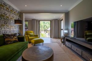a living room with a green couch and a flat screen tv at Lotsane Limpopo Luxury River Lodge in Sherwood