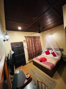 a bedroom with a bed with red pillows and a table at Ombak Dive Resort Perhentian Island in Perhentian Islands
