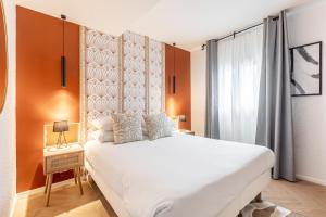a bedroom with a large white bed and an orange wall at Le Bastille By Sweett in Paris