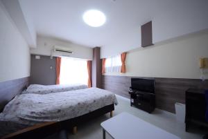 a bedroom with two beds and a television at Sumuka Asato Station 1K[F-5] in Naha