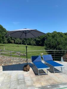 - 2 chaises bleues et un parasol sur la terrasse dans l'établissement La Dolce Vita chalet, à Massino Visconti