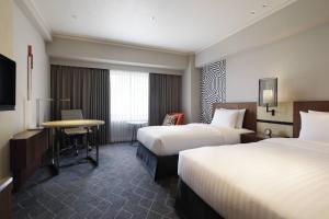 a hotel room with two beds and a table at Courtyard by Marriott Shin-Osaka Station in Osaka