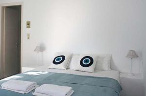 um quarto branco com uma cama com alvos nas almofadas em Galanis Place em Antiparos