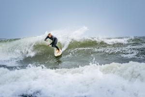 a man riding a wave on a surfboard in the ocean at Visit Örestrand in Strandbaden