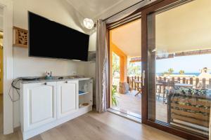salon z przesuwnymi szklanymi drzwiami prowadzącymi na taras w obiekcie Villetta Residence Porto Corallo w mieście Villaputzu