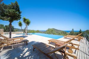 a resort with a pool and wooden benches and trees at Can Pla Roig con vistas al Mar y la Puesta de Sol in Sant Joan de Labritja