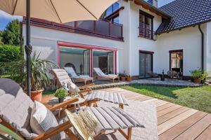 a patio with rocking chairs and an umbrella at Coastal Breeze Usedom in Heringsdorf