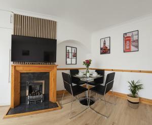 Un comedor con mesa y chimenea. en EcuaStay New Luxurious 4 Bedroom Home with Garden and parking, en Dagenham