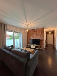 un salon avec un canapé et un mur de briques dans l'établissement BoleslaviaApartments - Apartament Arte 4, parking free, EV, à Bolesławiec