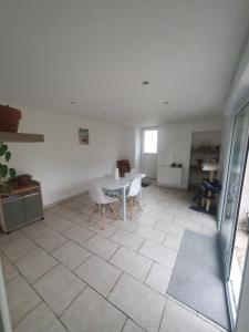 une chambre blanche avec une table et des chaises. dans l'établissement Chambre chez l'habitant avec petit déjeuner à 5 mins du Futuroscope, à Chasseneuil-du-Poitou 4 autres photos