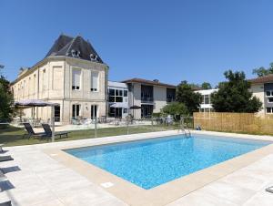 a large swimming pool in front of a building at Green Hôtels Bordeaux Arena in Latresne