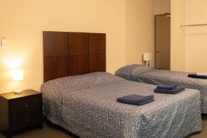 two beds in a hotel room with two blue towels on them at The Bexley Motel in Sydney