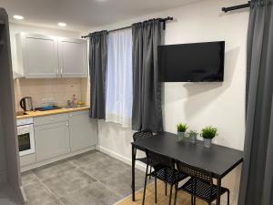 a kitchen with a table with chairs and a television on the wall at Akmene Center Apartment in Naujoji Akmenė
