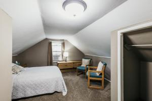 a attic bedroom with a bed and two chairs at Spacious & Updated MQT Home - HotTub - Backyard in Marquette