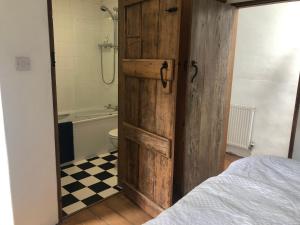 a bathroom with a wooden door with a tub and a toilet at Wisteria Cottage in Truro