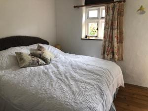 a bedroom with a white bed with two pillows on it at Wisteria Cottage in Truro