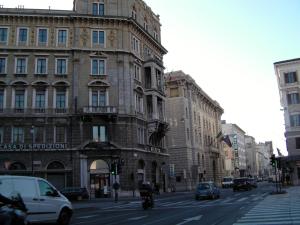 a building on a city street with cars and a motorcycle at Affittacamere Alla Stazione in Trieste