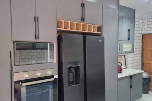 a kitchen with a stainless steel refrigerator and cabinets at Castletown Villa in Serowe