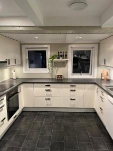 a kitchen with white cabinets and a tile floor at Sjarmerende hus i Vennesla in Vennesla