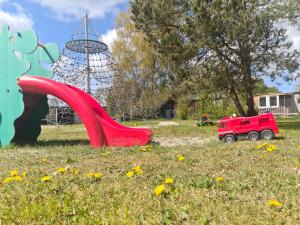 a playground with a red slide in a field at Garten-Ferienhaus Biendorf OT Westenbrügge in Uhlenbrook